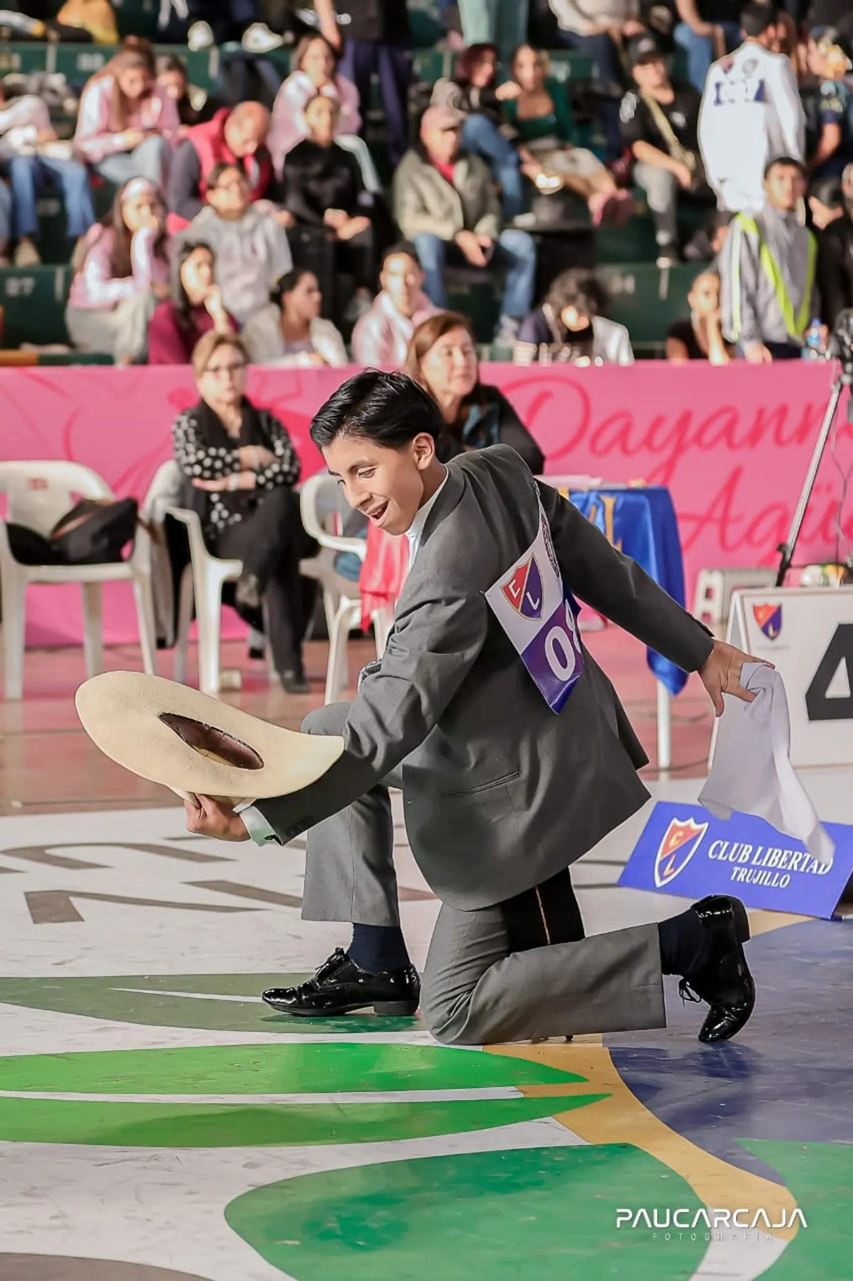 Bailarín de marinera norteña arrodillado alzando el sombrero