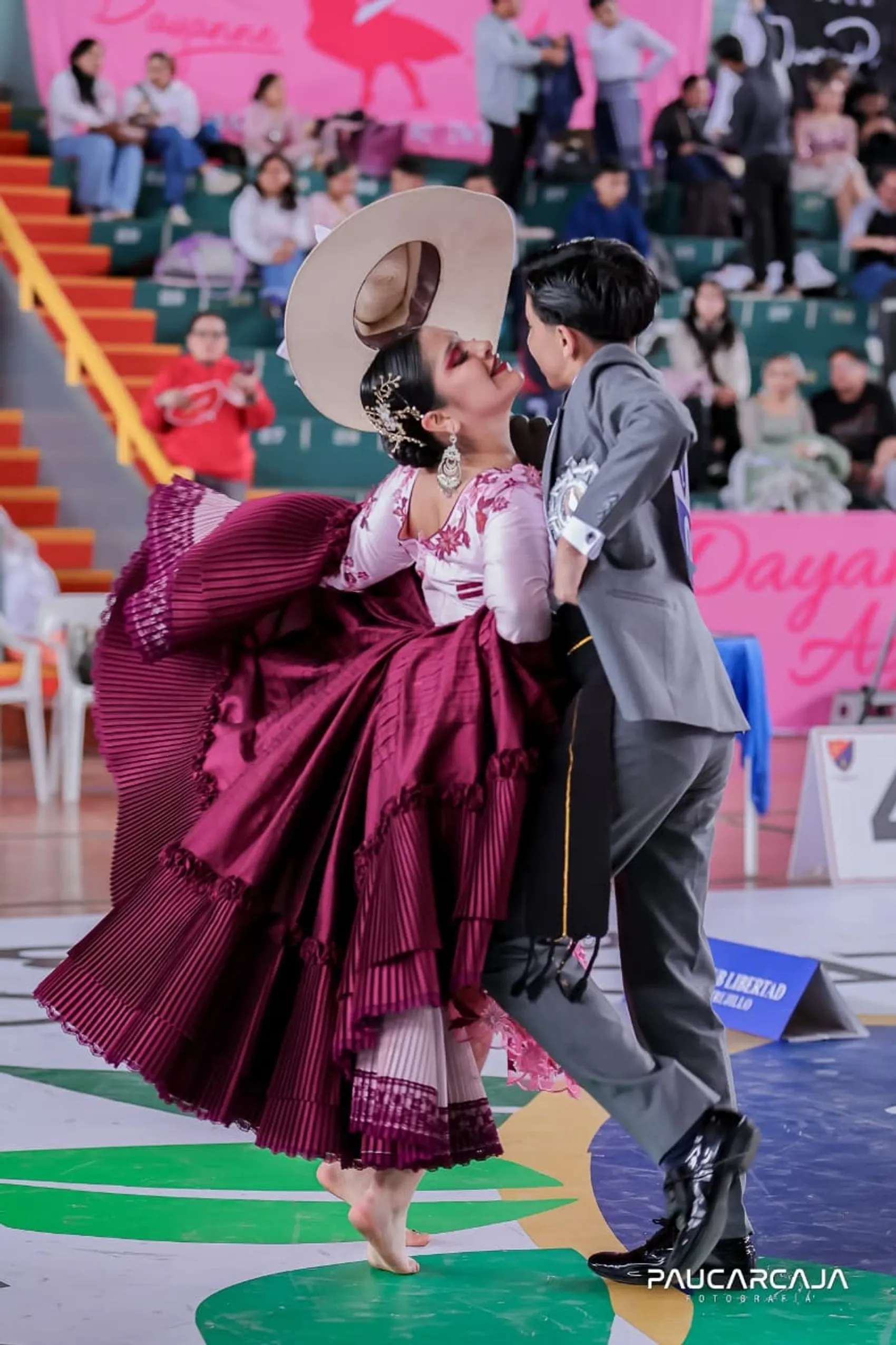 Pareja de marinera bailando en traje granate